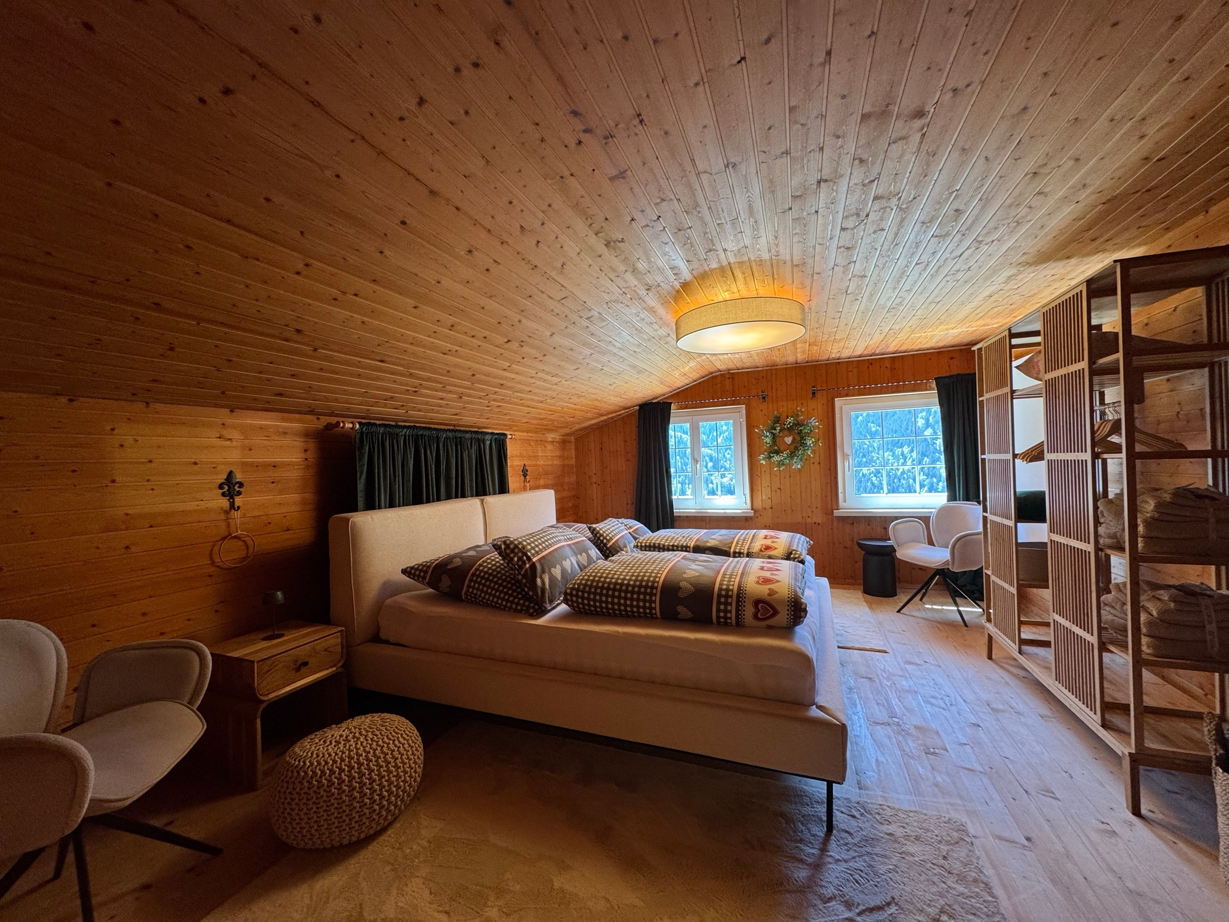 Bedroom 1 under the sloping roof with double bed and open wooden shelving