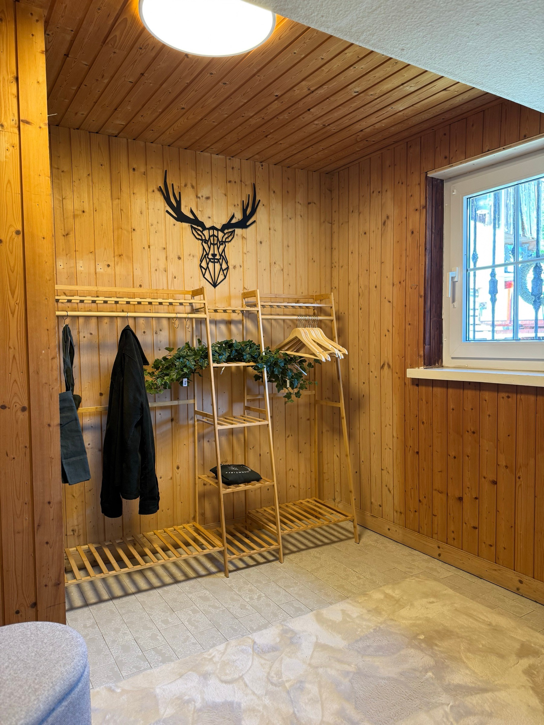 Wood-panelled cloakroom with clothes rack and stag wall decoration