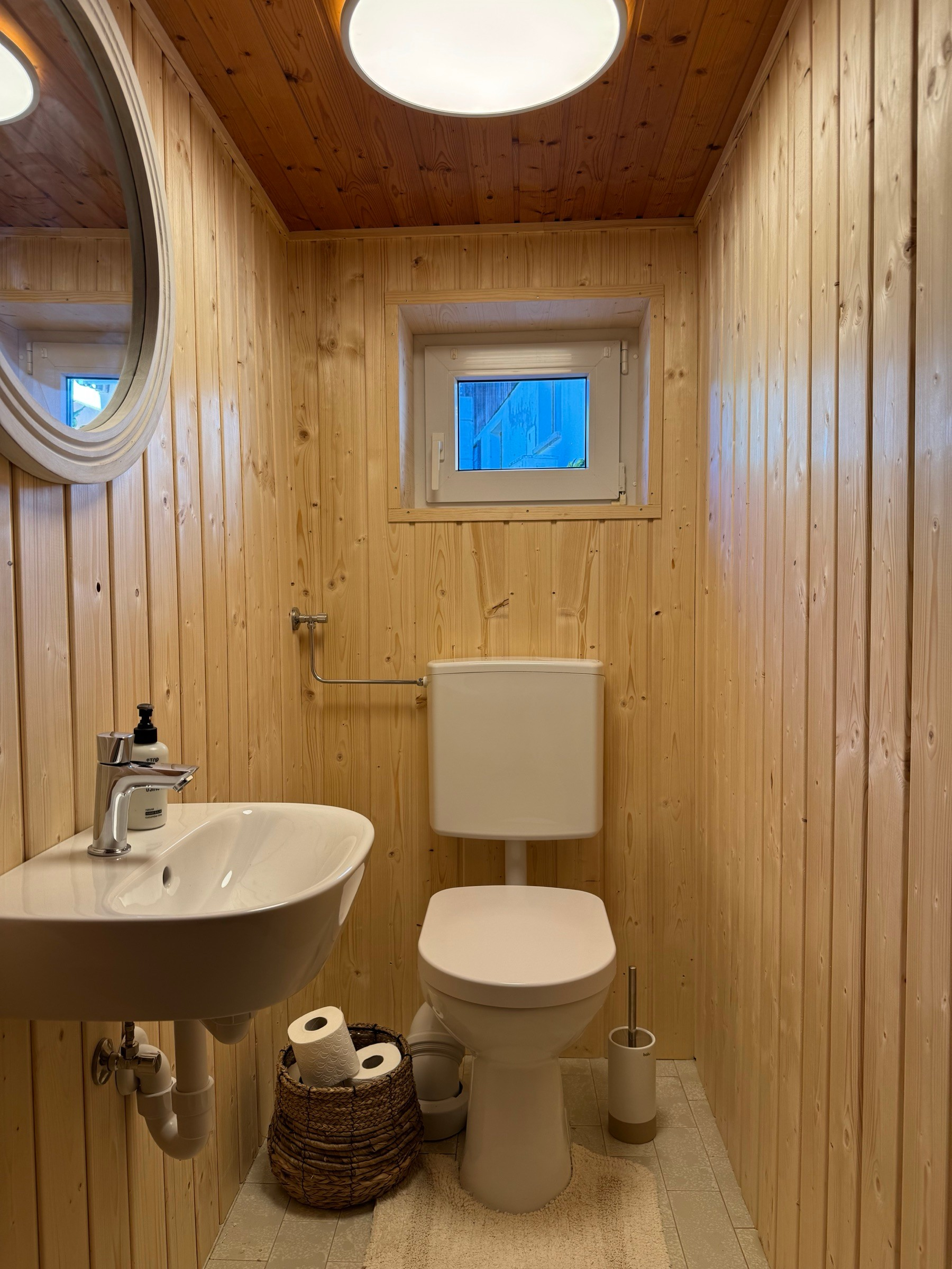 Guest WC with wood panelling, washbasin and round mirror