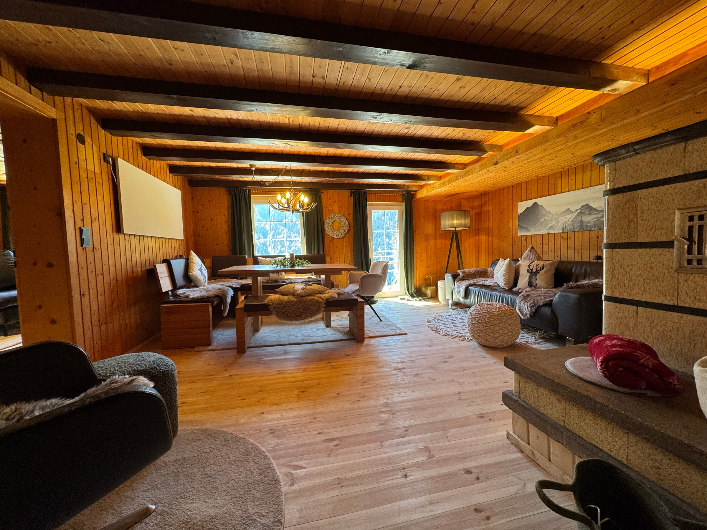 Open-plan living and dining area with wood panelling and dark ceiling beams
